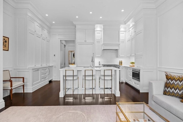 128 Marlborough St Unit 6, Boston, MA 02116 - kitchen with a decorative wall, dark wood-type flooring, white cabinets, a breakfast bar, and ornamental molding