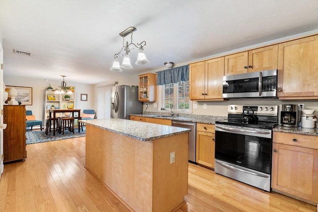 kitchen with light hardwood / wood-style flooring, hanging light fixtures, stainless steel appliances, a center island, and a chandelier