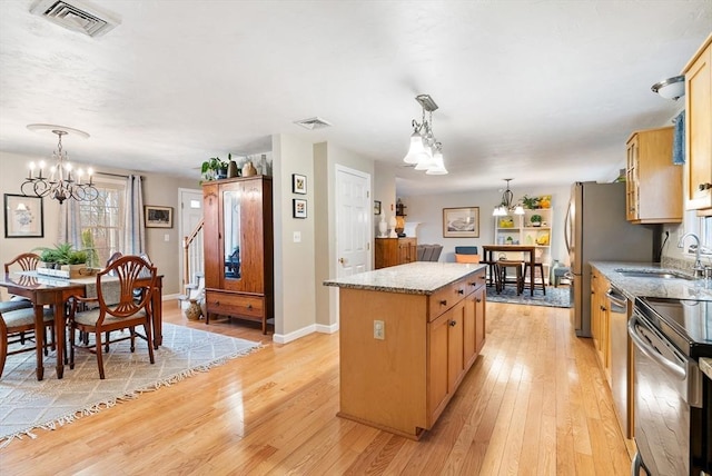 kitchen featuring a kitchen island, sink, hanging light fixtures, light stone counters, and an inviting chandelier