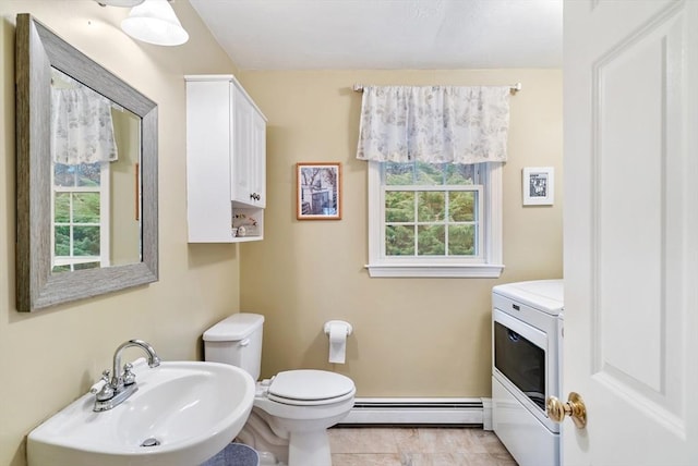 bathroom featuring toilet, washer / dryer, sink, a baseboard radiator, and tile patterned flooring