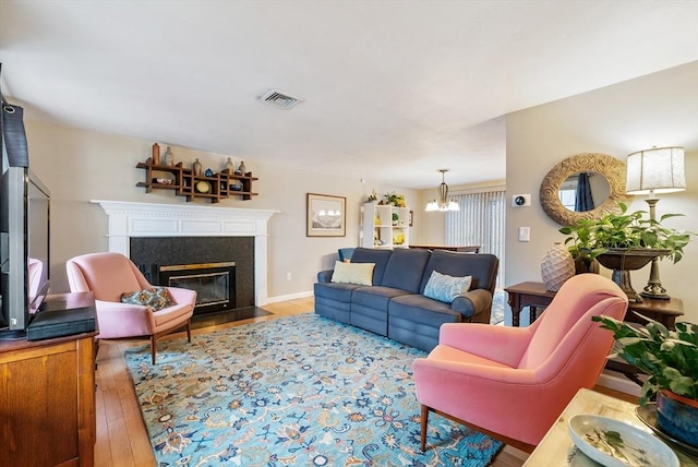 living room featuring hardwood / wood-style flooring, a notable chandelier, and a fireplace