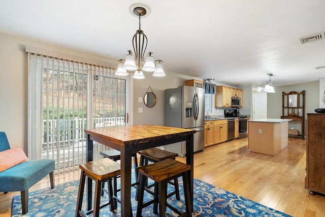 dining room with sink, a chandelier, and light hardwood / wood-style floors