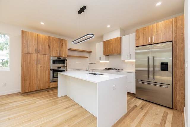 93 Griswold St Unit 93, Cambridge, MA 02138 - kitchen featuring appliances with stainless steel finishes, a sink, light wood finished floors, decorative backsplash, and light countertops