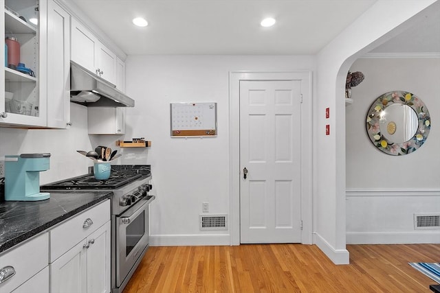 kitchen with under cabinet range hood, visible vents, white cabinetry, and high end range