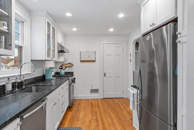 kitchen with visible vents, white cabinets, glass insert cabinets, appliances with stainless steel finishes, and a sink