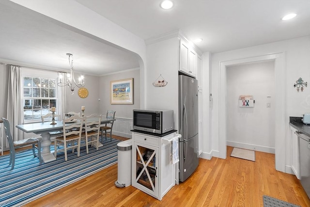 kitchen featuring white cabinets, dark countertops, decorative light fixtures, stainless steel appliances, and light wood-style floors