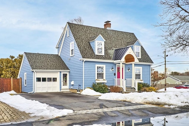 cape cod house with a garage, aphalt driveway, roof with shingles, and a chimney