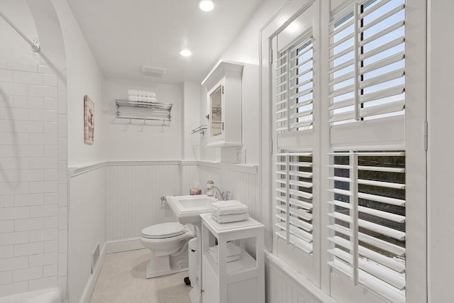 full bath with toilet, recessed lighting, a sink, wainscoting, and tile patterned floors