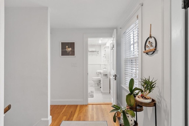 hallway featuring light wood-style flooring and baseboards