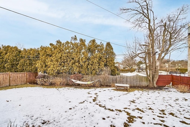 yard layered in snow featuring a fenced backyard