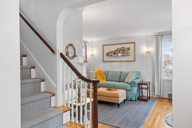 sitting room featuring arched walkways, visible vents, light wood-style flooring, and stairs