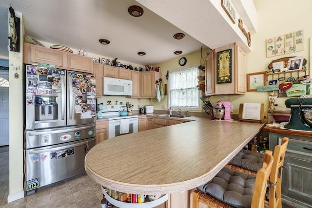 64 Porcupine Point Rd, Tolland, MA 01034 - kitchen with white appliances, light brown cabinetry, a sink, a peninsula, and a breakfast bar