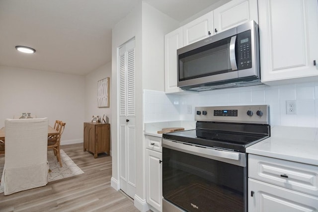 45 Macy St Unit 200A, Amesbury, MA 01913 - kitchen featuring appliances with stainless steel finishes, light countertops, white cabinets, decorative backsplash, and light wood-style flooring