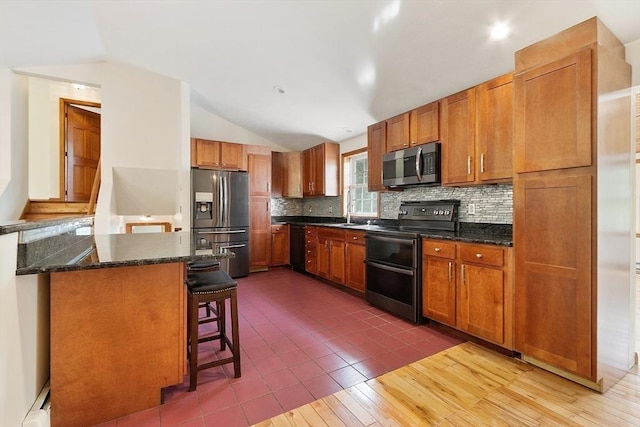 728 River St, Winchendon, MA 01475 - kitchen featuring stainless steel appliances, vaulted ceiling, tasteful backsplash, a breakfast bar, and brown cabinetry