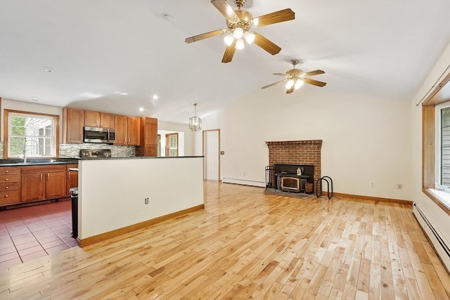 728 River St, Winchendon, MA 01475 - kitchen featuring stainless steel microwave, a baseboard radiator, dark countertops, a sink, and light wood-style flooring