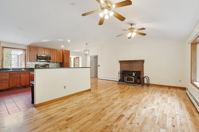 728 River St, Winchendon, MA 01475 - kitchen featuring stainless steel microwave, a baseboard heating unit, a sink, dark countertops, and light wood-style floors