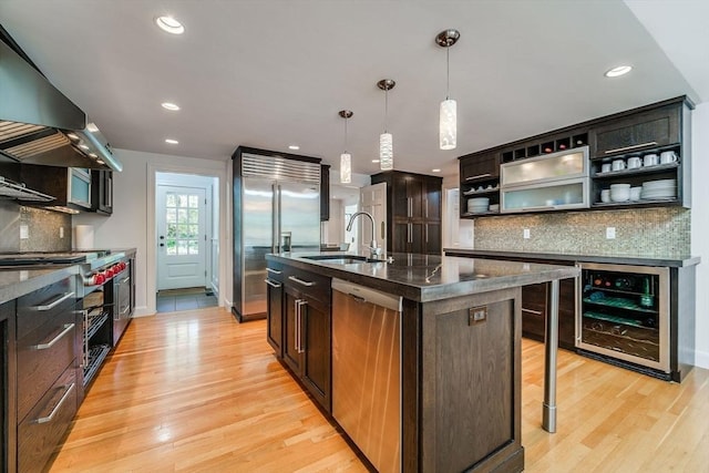 kitchen with open shelves, high end appliances, beverage cooler, light wood-style floors, and a sink