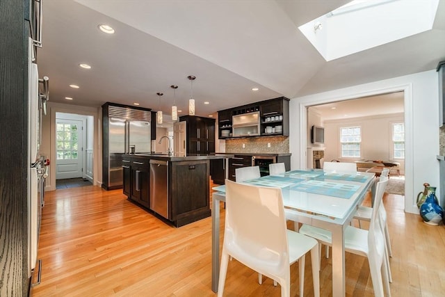 dining space with recessed lighting, a skylight, and light wood-style floors