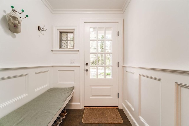 entryway with crown molding, dark tile patterned flooring, a wainscoted wall, and a decorative wall