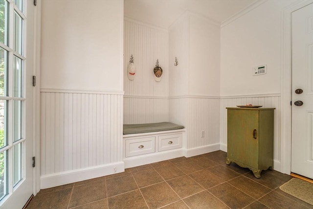 mudroom featuring crown molding, a wainscoted wall, and dark tile patterned flooring