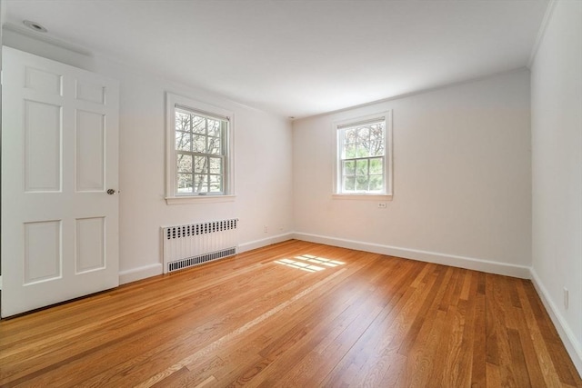 unfurnished room featuring radiator heating unit, baseboards, and light wood-style flooring