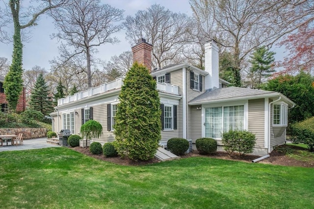 view of front of home featuring a chimney, a patio area, and a front yard