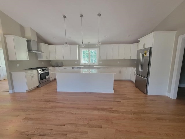 kitchen with hanging light fixtures, a kitchen island, white cabinetry, appliances with stainless steel finishes, and light hardwood / wood-style floors