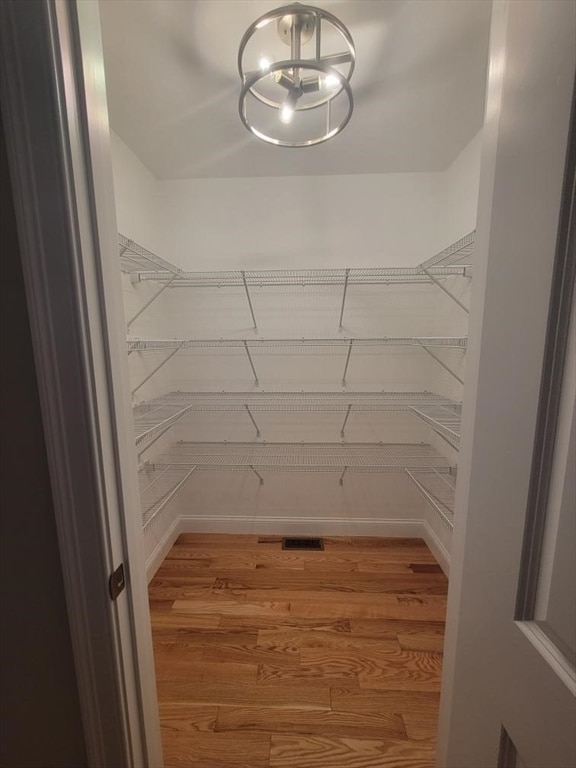 spacious closet with a notable chandelier and hardwood / wood-style flooring