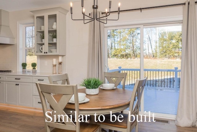 dining area with a notable chandelier, plenty of natural light, and light wood-type flooring