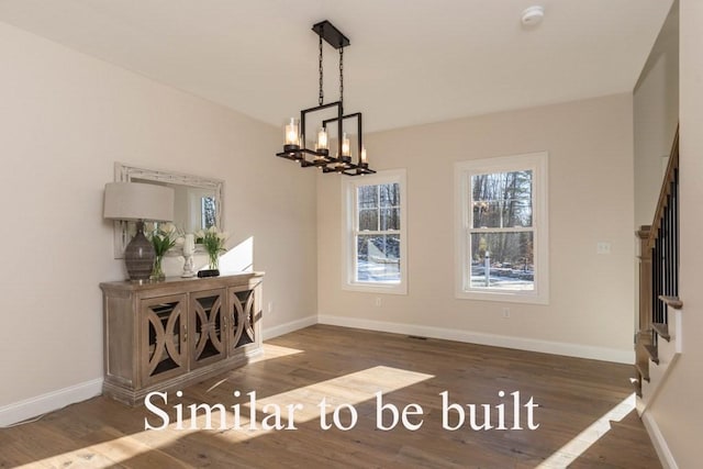 unfurnished dining area featuring a notable chandelier, stairway, and wood finished floors