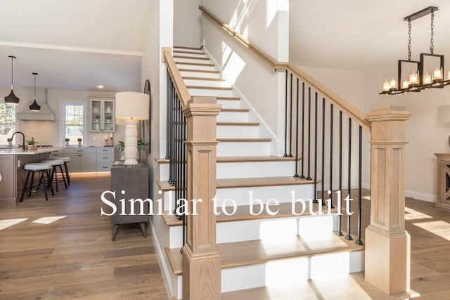 stairway featuring baseboards, a notable chandelier, and wood finished floors