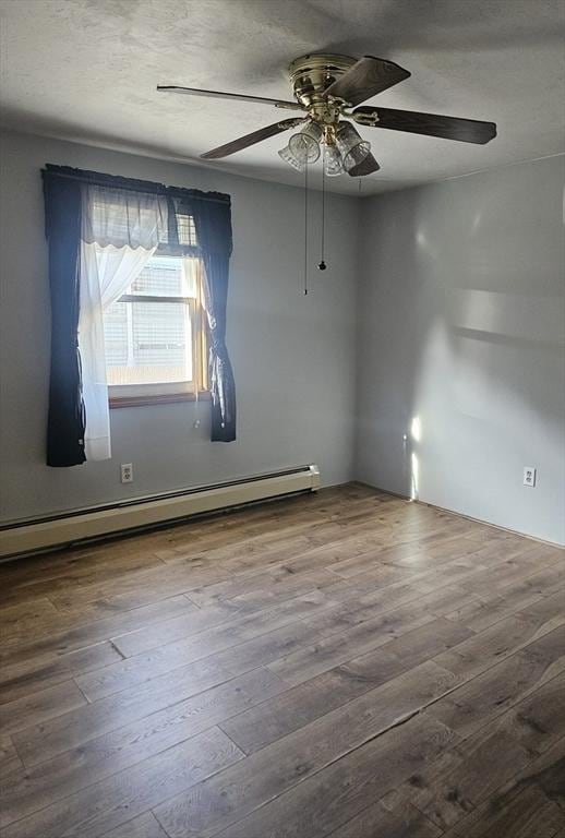 unfurnished room with ceiling fan, wood finished floors, and baseboard heating