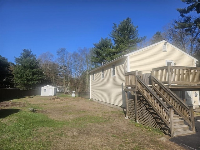 exterior space with a lawn, a wooden deck, stairway, an outdoor structure, and a shed