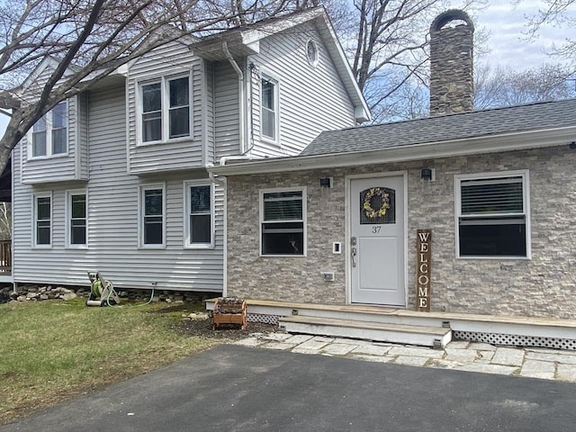 view of front of property with roof with shingles and a chimney