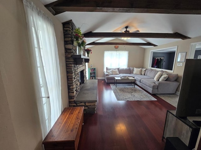 living area featuring ceiling fan, a stone fireplace, vaulted ceiling with beams, and wood finished floors