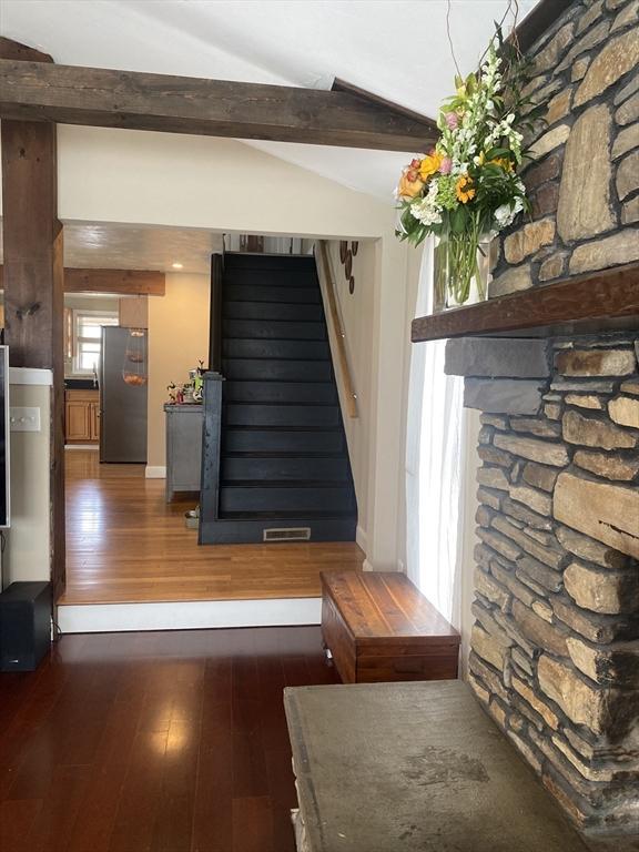 staircase featuring lofted ceiling with beams, visible vents, and hardwood / wood-style floors