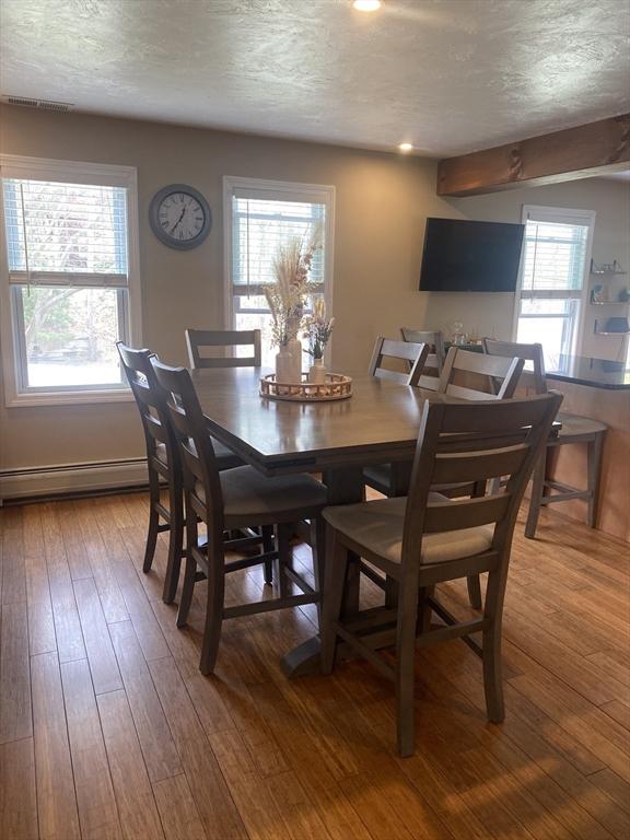 dining space featuring visible vents, a baseboard radiator, a textured ceiling, and hardwood / wood-style floors