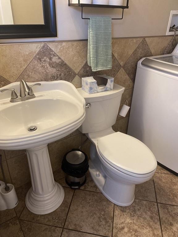 bathroom with washer / dryer, tile patterned floors, toilet, and tile walls
