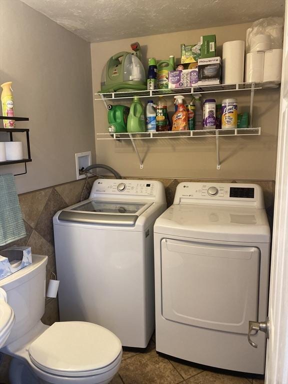 laundry area featuring laundry area, a textured ceiling, independent washer and dryer, tile walls, and tile patterned flooring
