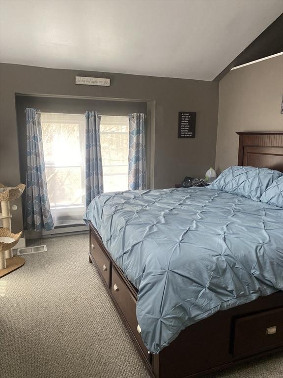bedroom featuring carpet floors, lofted ceiling, and visible vents