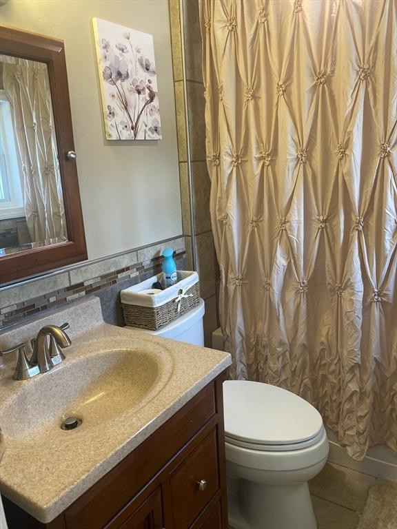full bathroom featuring a shower with curtain, tile walls, tile patterned flooring, vanity, and toilet