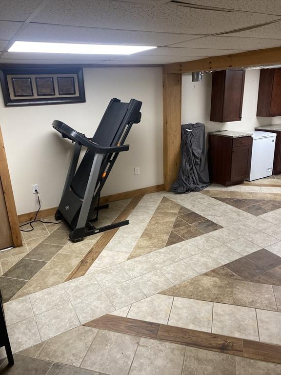exercise area featuring baseboards and a drop ceiling