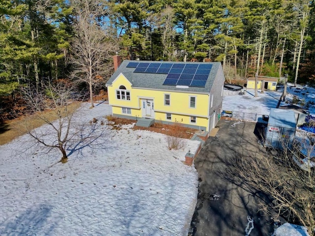 exterior space featuring fence, a chimney, and roof mounted solar panels