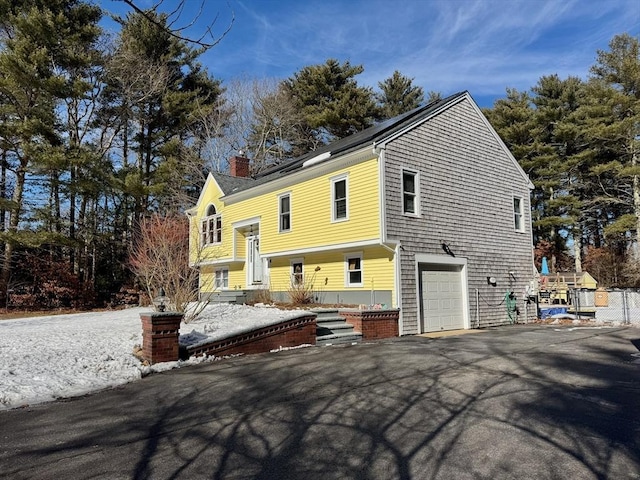 view of front of home with a chimney and an attached garage