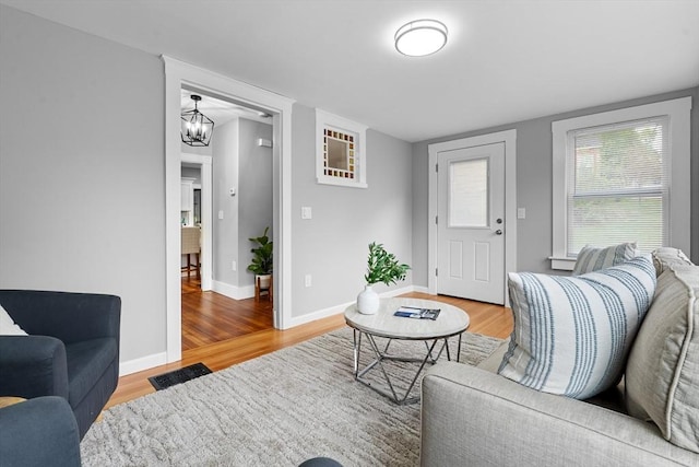 living room with light wood-type flooring, baseboards, and a chandelier