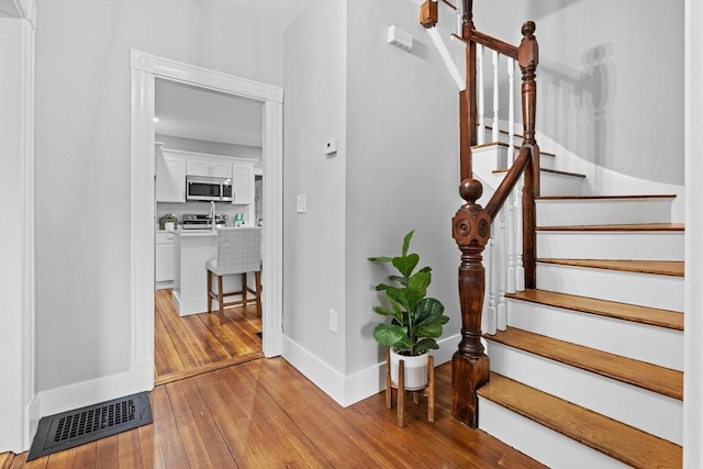 stairway with wood-type flooring and baseboards