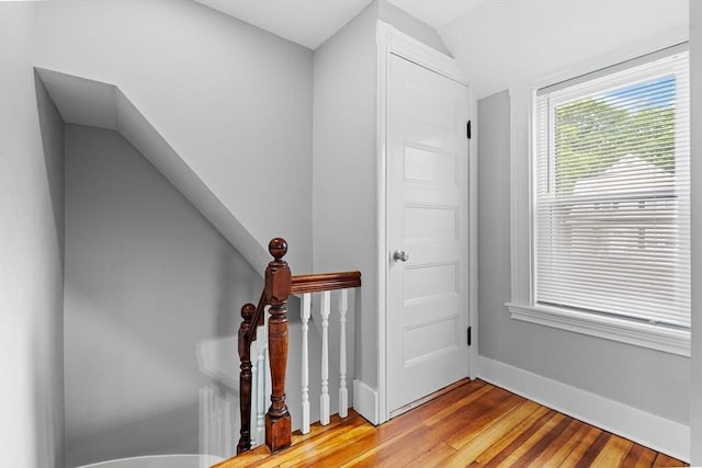 staircase with wood finished floors, baseboards, and lofted ceiling