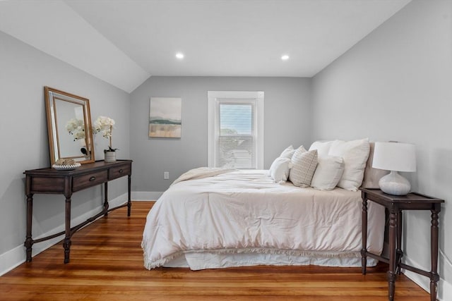 bedroom with wood finished floors, lofted ceiling, baseboards, and recessed lighting