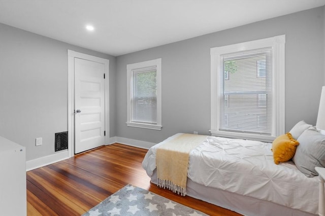 bedroom featuring baseboards, multiple windows, wood finished floors, and recessed lighting