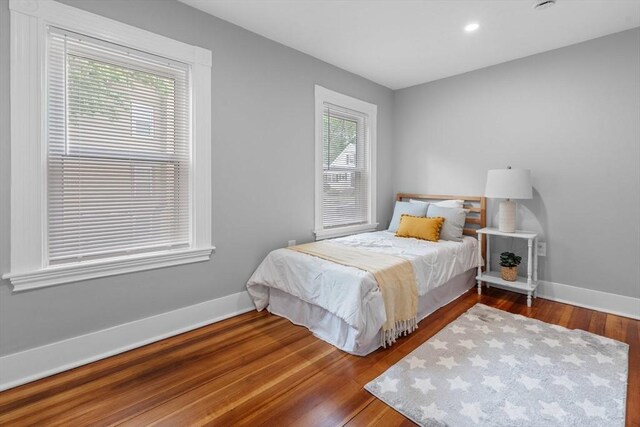 bedroom featuring multiple windows, baseboards, wood finished floors, and recessed lighting